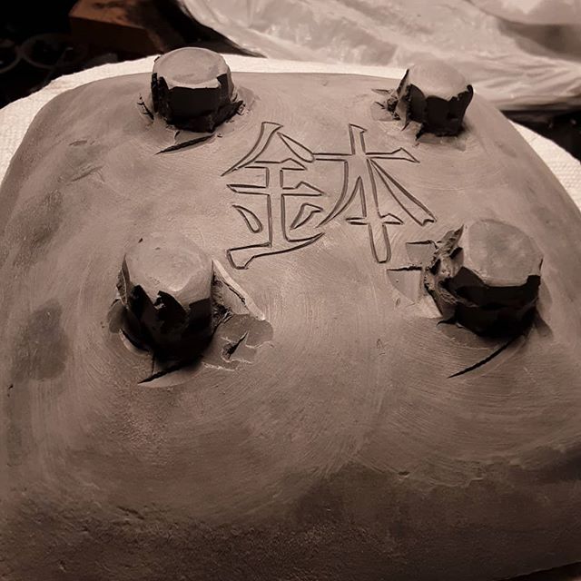 Kanji style writing on a clay pot in process
